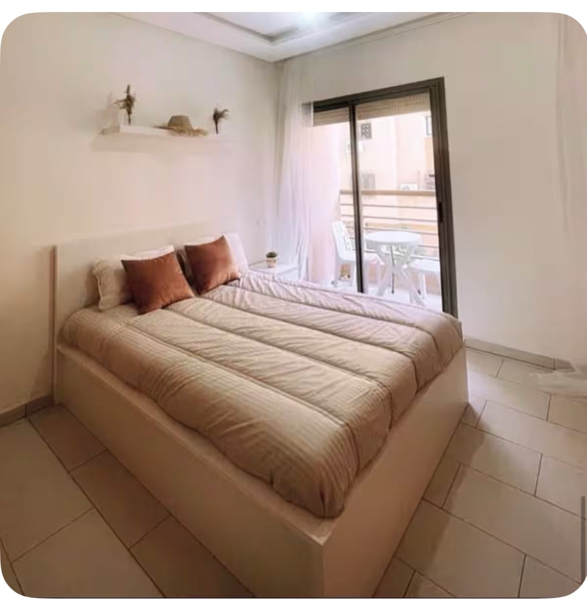 Studio apartment rental in central Marrakech (Semlalia) &mdash; bedroom with terracotta cushions and doorway opening onto the private terrace