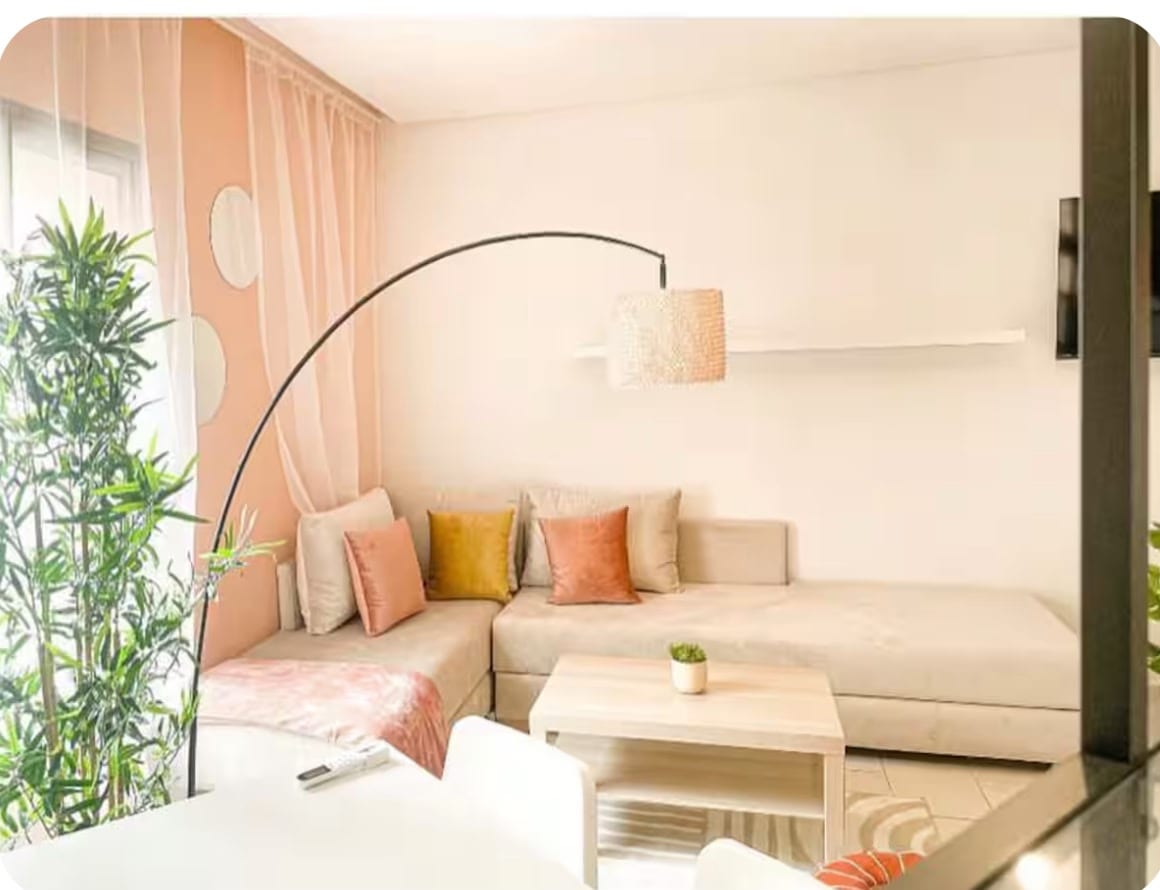 Cozy boho studio apartment for rent in Marrakech Semlalia &mdash; living room corner with arched lamp, soft pillows and bamboo plant